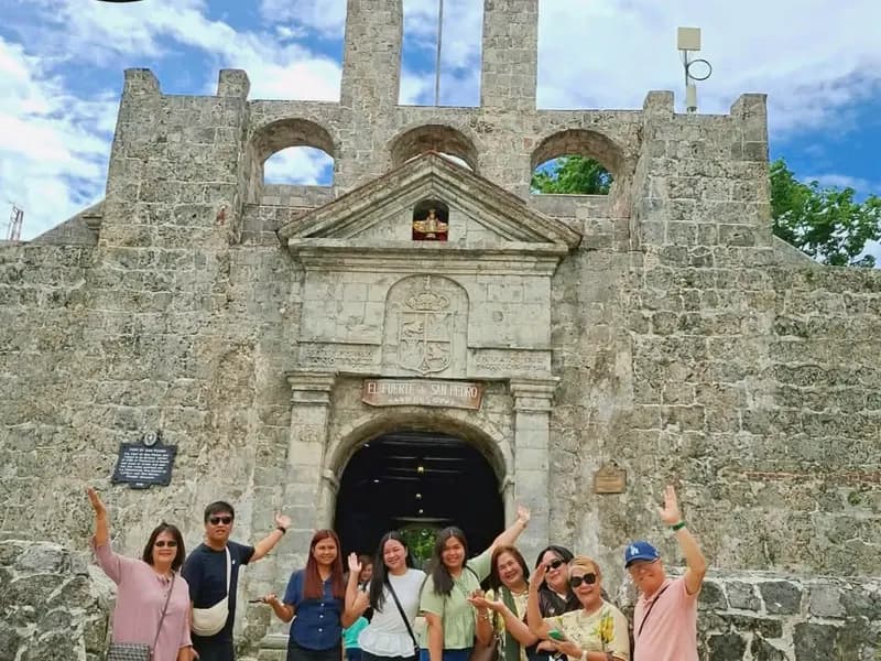Jushel guests waving in front of the stone gate of Fort San Pedro