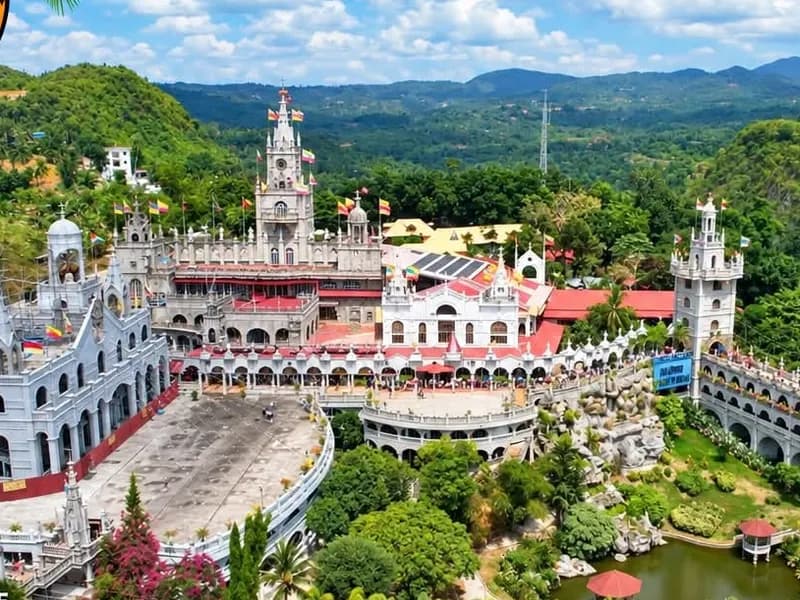 Aerial view of the castle-like Simala Shrine surrounded by green hills