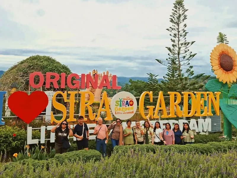 Guests by the colorful Sirao Garden sign with flowers and sunflowers