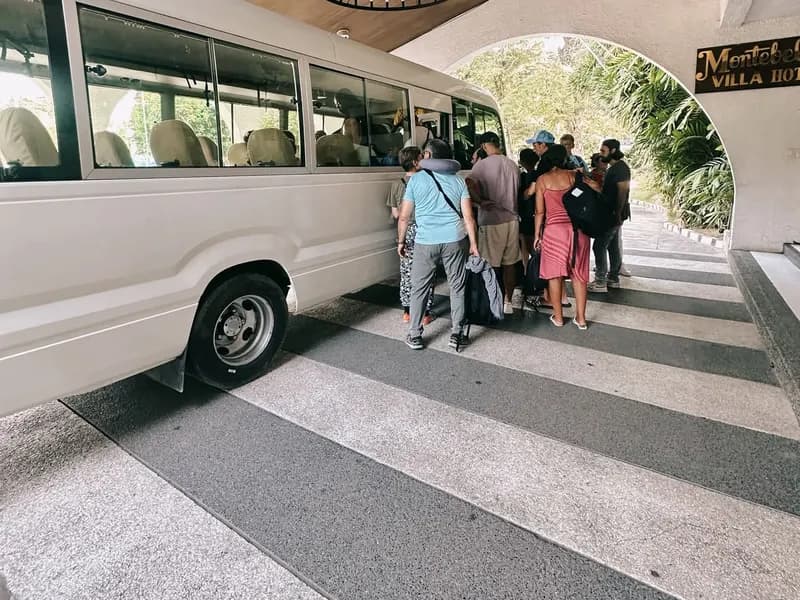 Guests boarding a white coaster bus at a resort entrance