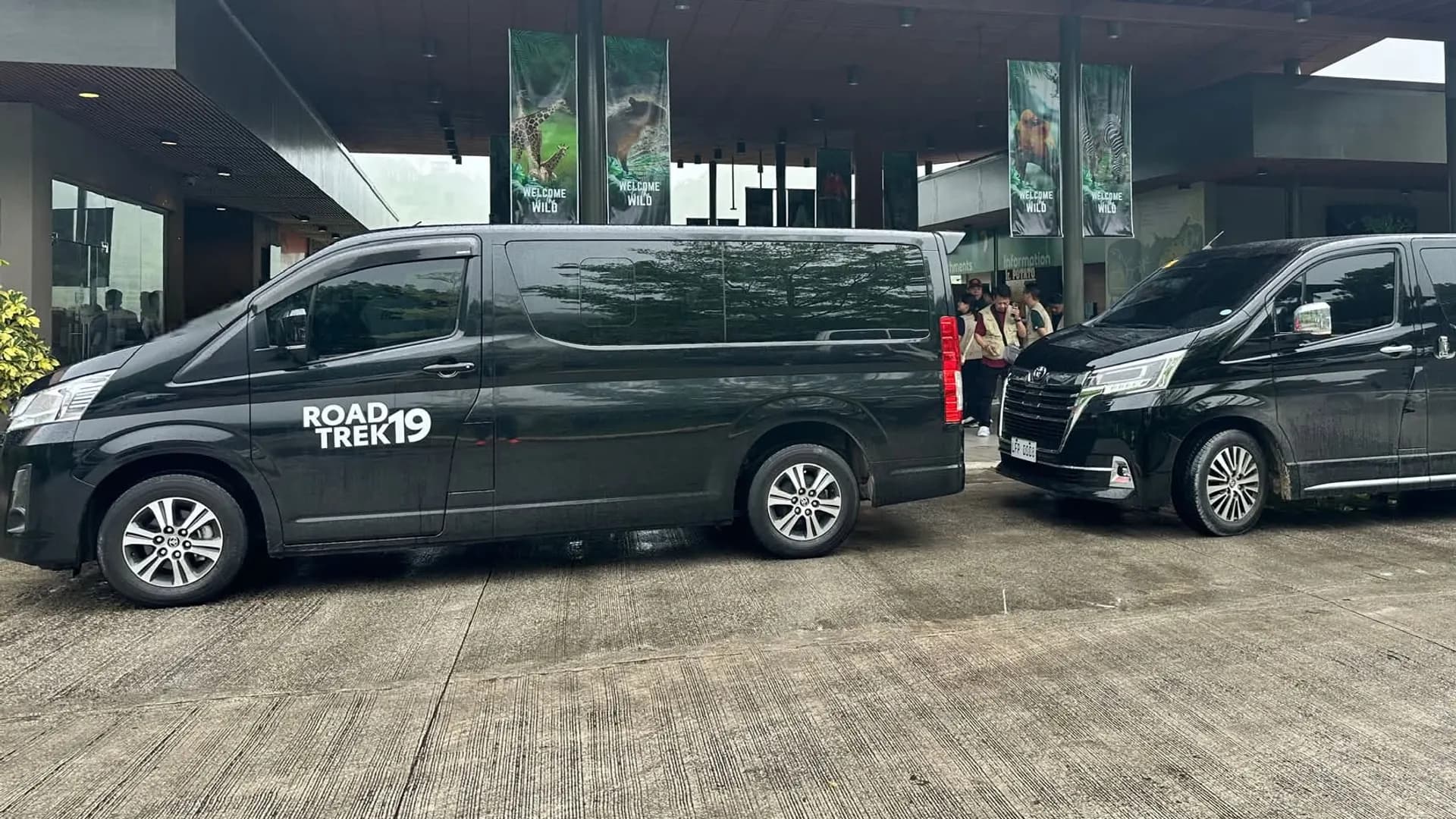 Two black Jushel tourist vans parked outside a Cebu terminal